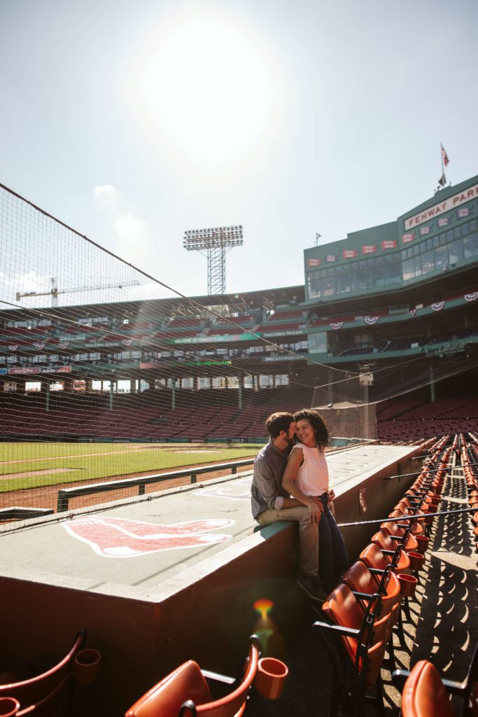Couple poses by the dugout at Fenway Park during Boston engagement photos