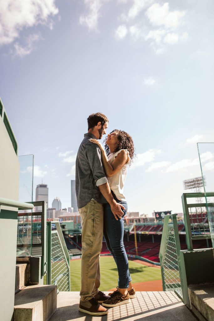 Couple embracing in the stands at Fenway park during their Boston engagement photo session