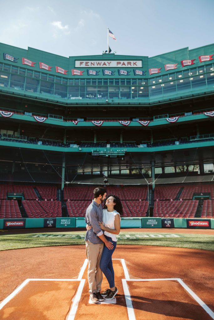 Couple stands at home plate at Fenway during their Boston engagement photos